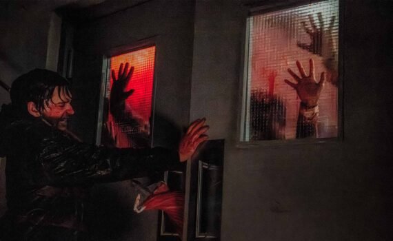 Austin Abrams en Resident Evil 2026 erncerrado manos zombies en cristal